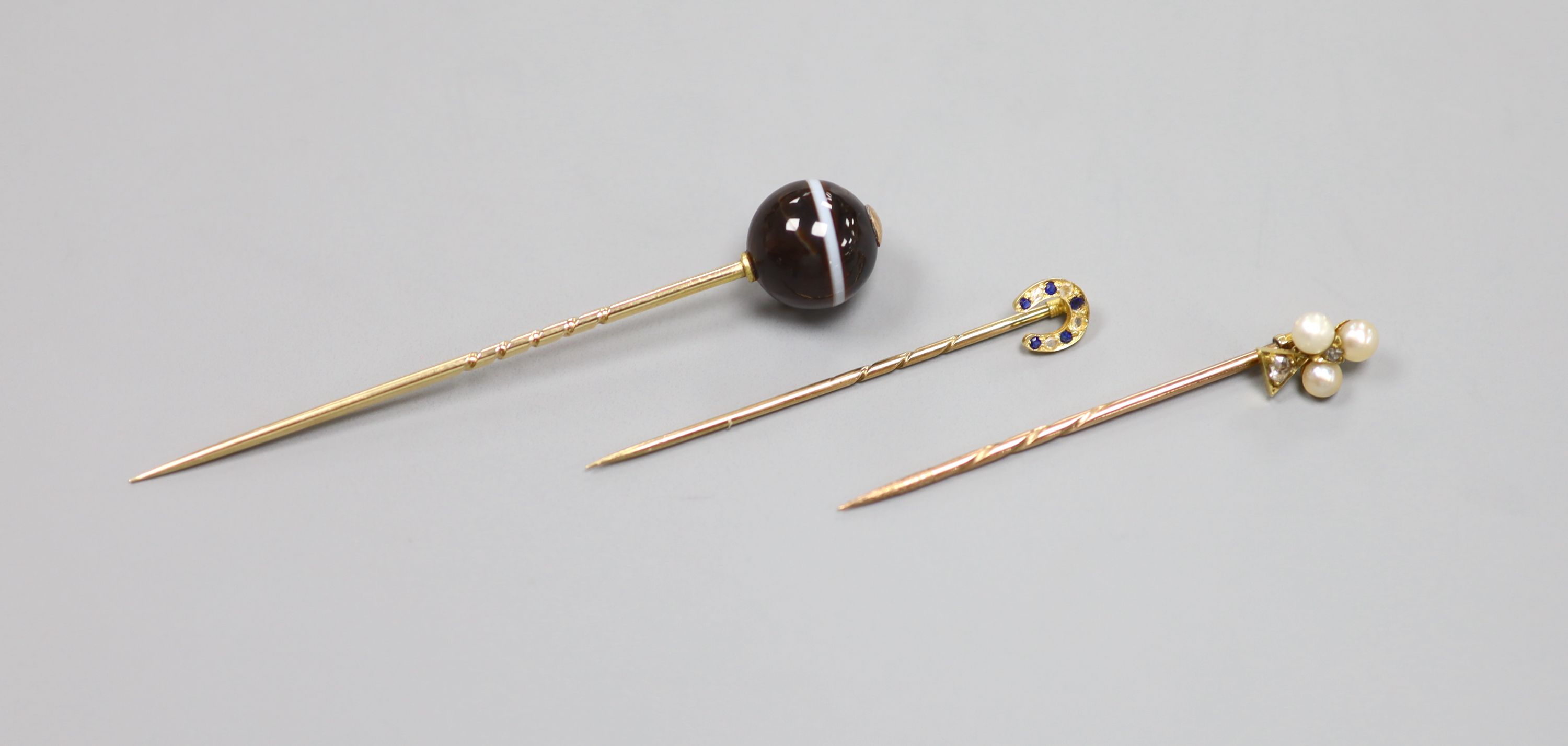 Three assorted early 20th century yellow metal and gem set stick pins